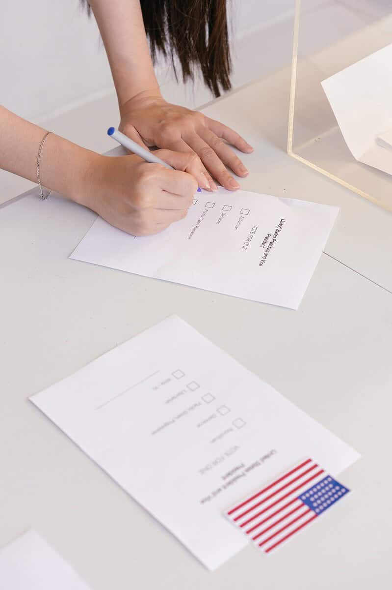 An individual is marking a ballot paper at an election booth, symbolizing democratic participation.