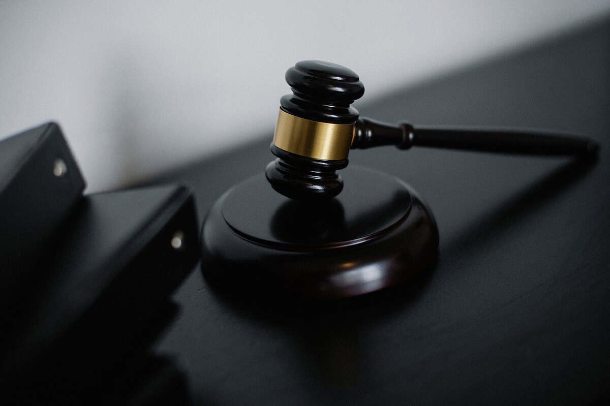 High angle of shiny wooden ceremonial mallet with golden detail placed on judge tale near documents folders