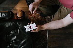 A person holding a smartphone with a dating app displayed while sitting on a leather chair.